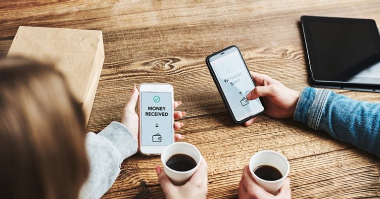 two friends transferring money at coffee shop